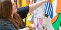 a person holding coloured paper to a wall