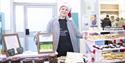 A stallholder selling cakes and brownies smiles at the camera, stood in front of her stall