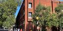 a red brick building with green trees and blue sky