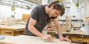 a man wearing safety goggles on his head sanding a flat piece of wood