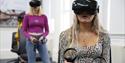 Two students wearing VR headsets in a bright classroom