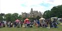 Competitors line up with their dogs in front of food and drink stalls within the grounds of Thoresby Park