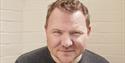 A headshot of our artist in residence, Mark who has short red hair and wears a brown t-shirt