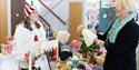 A stallholder selling knitted items smiles as she talks to a customer