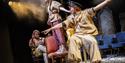 The Trials - Three young people on a disused theatre stage wear clothes made from hessian sacks and coffee bags and sit on chairs one behind the other
