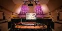 A wide shot showing the Royal Concert Hall. Children are singing on the stage, with a screen saying "An Inspired Christmas Concert" behind them