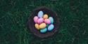 Photo of colourful easter eggs in a wicker basket.