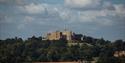 Belvoir Castle in the distance on a hilltop surrounded by woodland