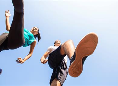 Photo of two runners, looking up at them from beneath their trainers