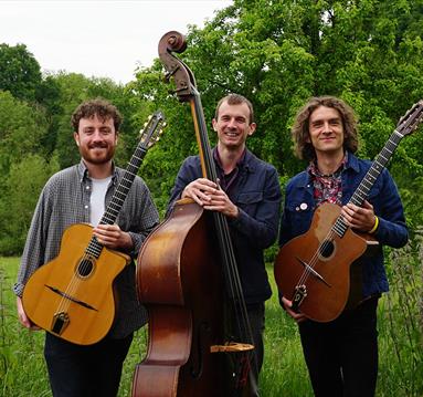 Photo of the Trio holding their instruments, standing in a field