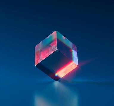 Image shows a clear glass cube with pink and blue lighting inside. 