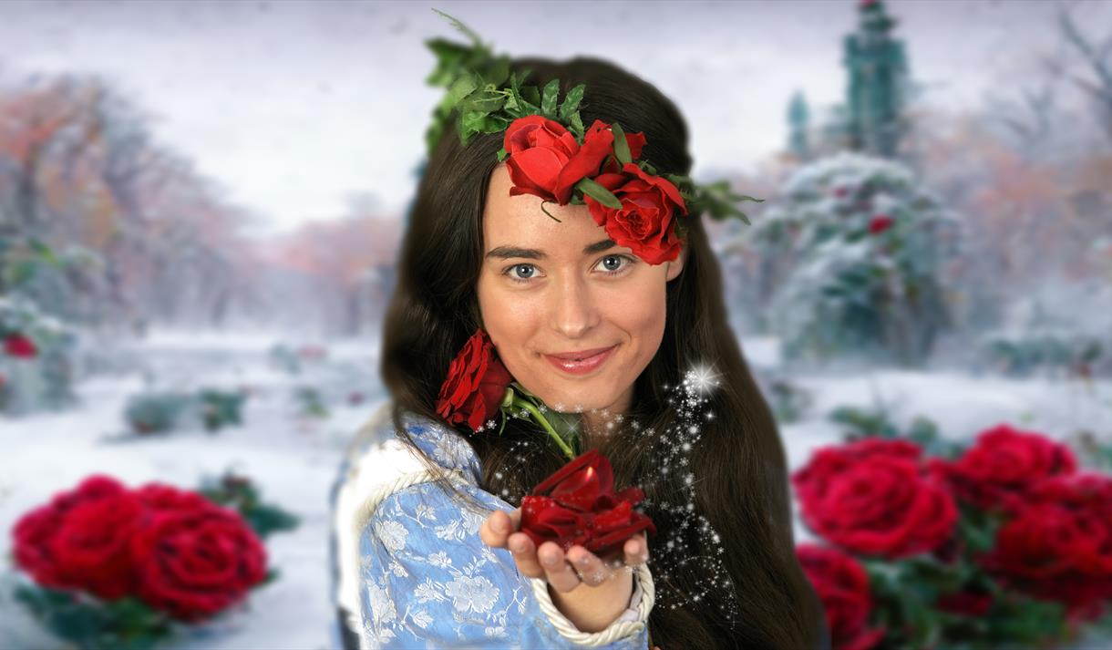 Image of a woman handing a rose to the viewer. In the background, there is a soft snowfall covering a beautiful garden,