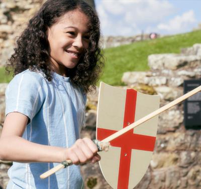 A young child stands holding a wooden sword and St. Georges Cross shield