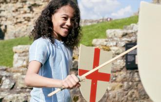 A young child stands holding a wooden sword and St. Georges Cross shield