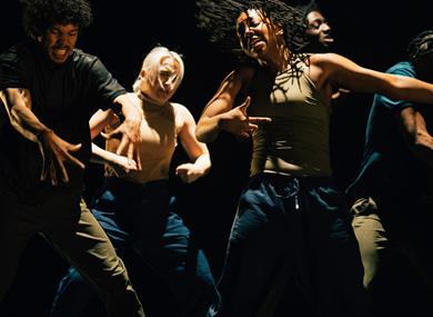 Photo of a dance troupe on stage, in action.