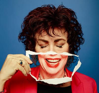 Photo of Ruby Wax holding a smile over her own face
