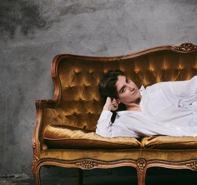 Photo of Sarah Keyworth lounging on a velvet couch