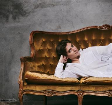 Photo of Sarah Keyworth lounging on a velvet couch