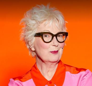 Photo of Jenny Eclair in front of a vibrant orange background