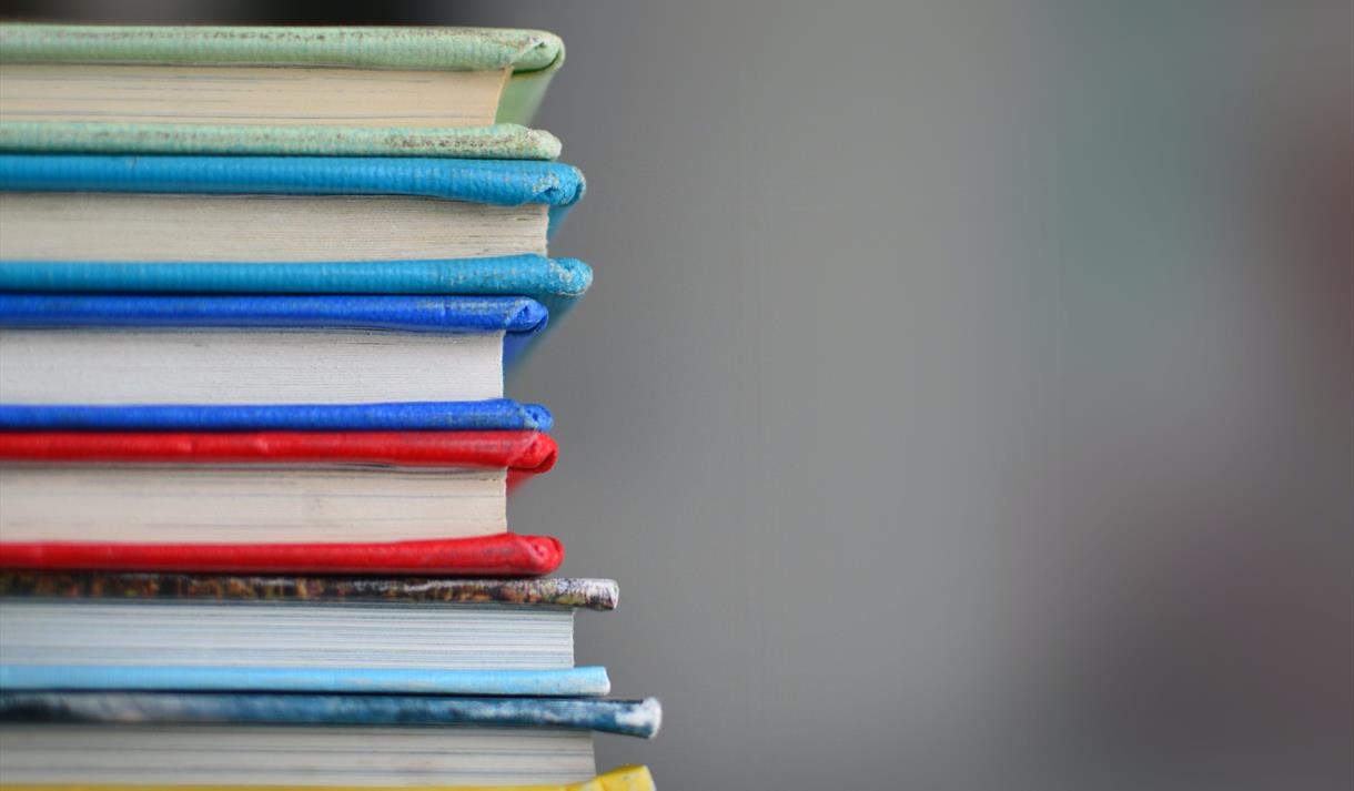 Photo of a stack of colourful books.
