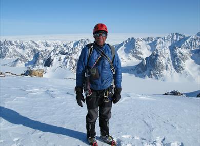 Photo of mountaineer Simon Yates on top of a snow covered mountain.
