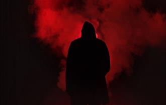 The image shows a black figure stood in red smoke.