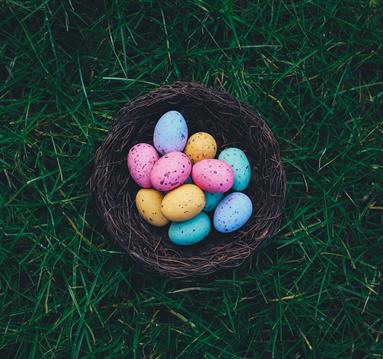 Photo of colourful easter eggs in a wicker basket.