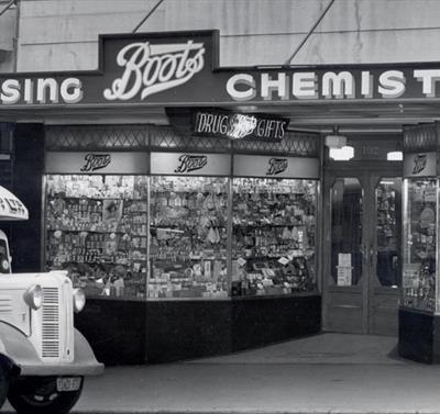Black and white photo of an old Boots store front.