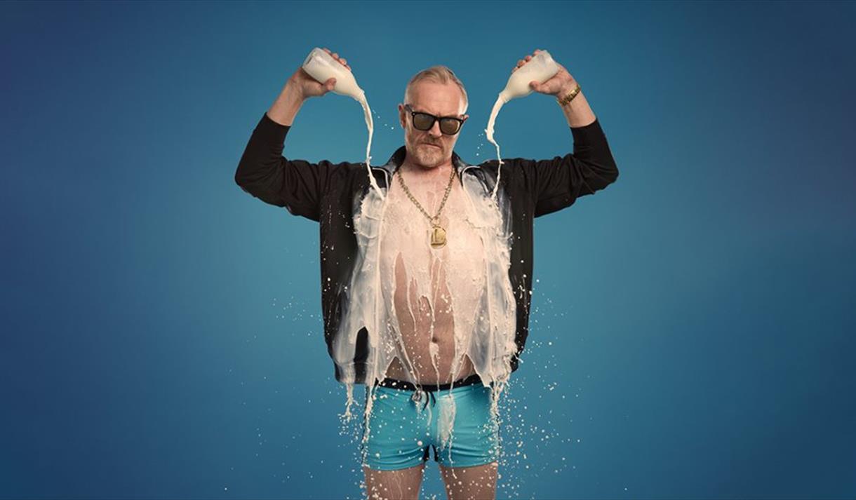 Show poster for Greg Davies new show showing him in underpants with an open shirt, pouring milk on himself.