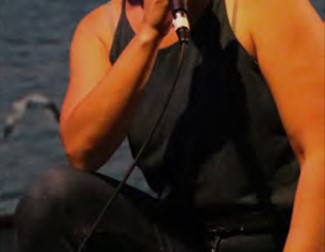 Image of Ayse Balko half kneeling talking into a microphone
