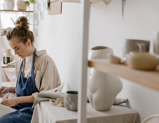 A Woman Sitting Beside the the Ceramic Display Shelves
