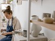A Woman Sitting Beside the the Ceramic Display Shelves
