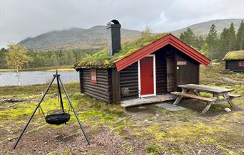 Tømmerhytte med torvtak, i fjellandskap