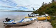 Motorbåter og kanoer på sandstrand