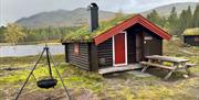 Tømmerhytte med torvtak, i fjellandskap