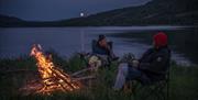 Personer ved bål ved Lomnessjøen. Sommernatt, fullmåne.