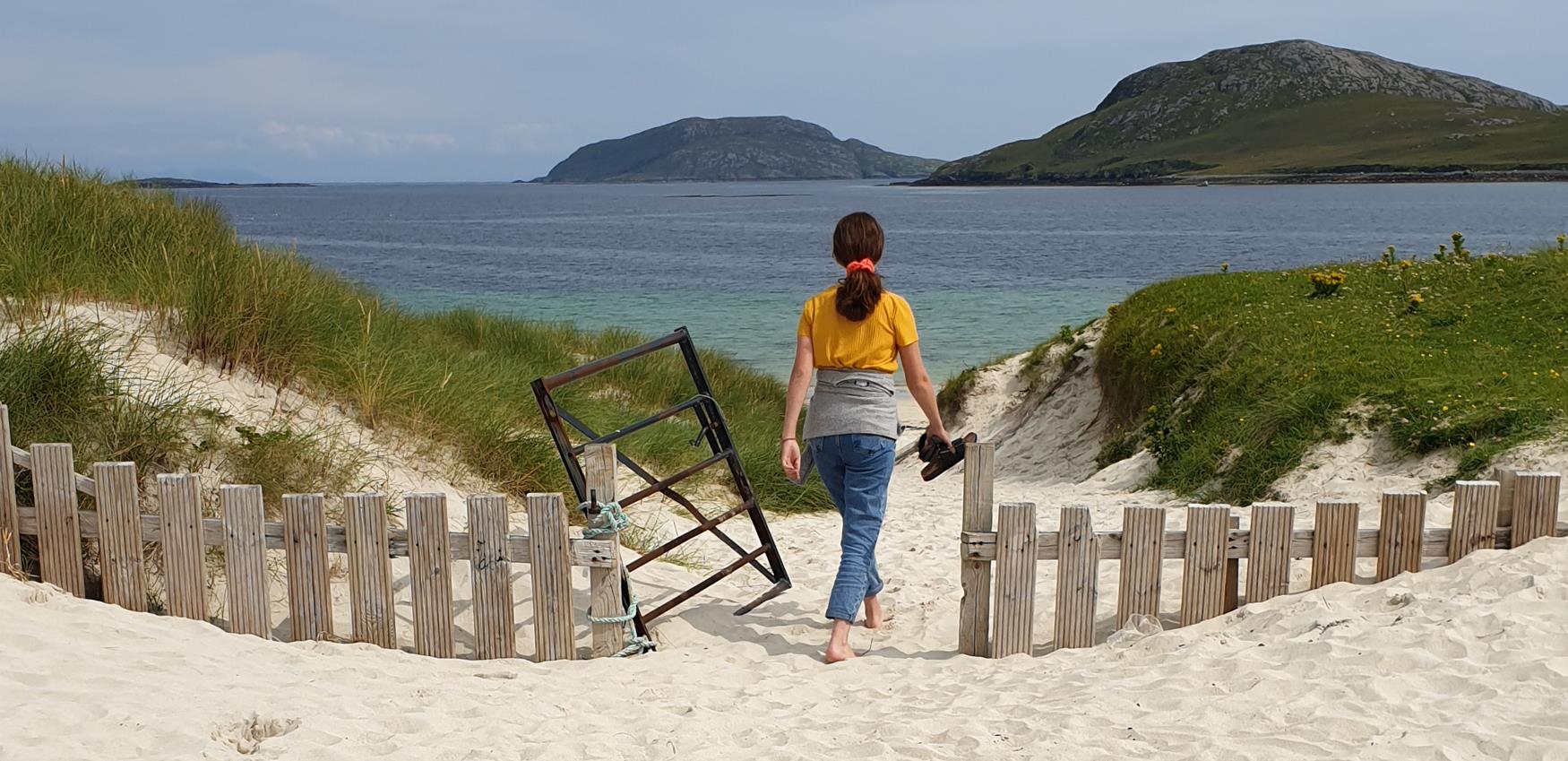 Feale walking through the gate to Vatersay Beach
