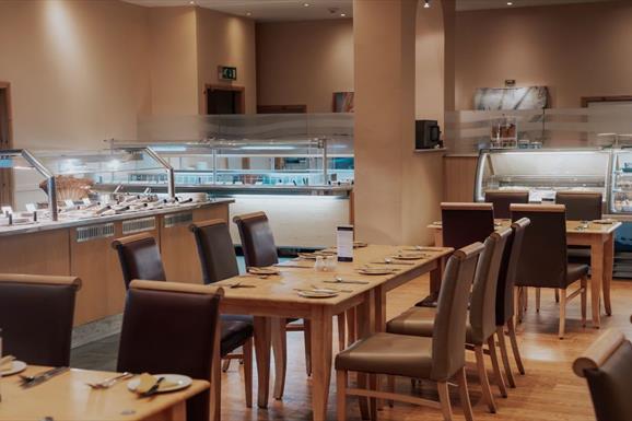 Spacious restaurant with carvery filled with numerous tables and chairs.