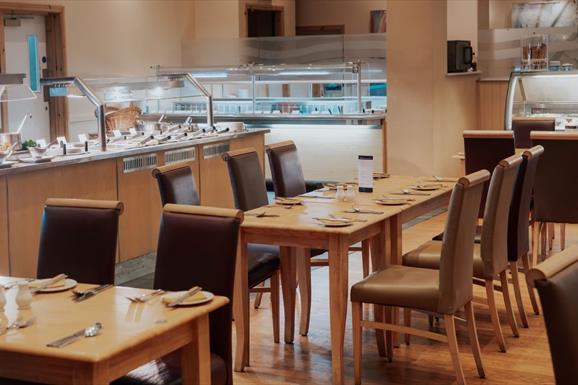 Spacious restaurant with carvery filled with numerous tables and chairs.