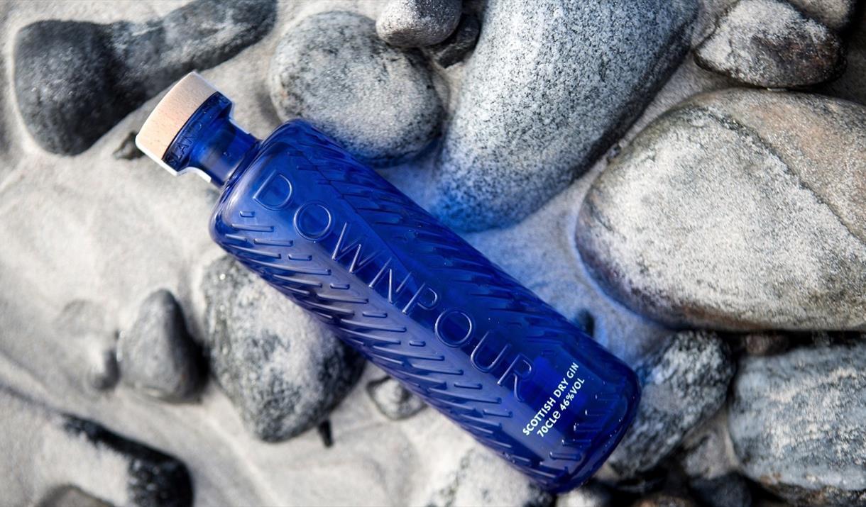 North Uist Distillery's Scottish Dry Gin, sitting on white sand, overlooking the sea