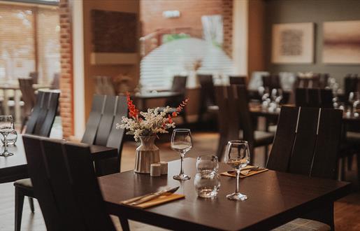 Cleaver Restaurant at the Cabarfeidh Hotel in Stornoway with tables and chairs in front of a brick wall.