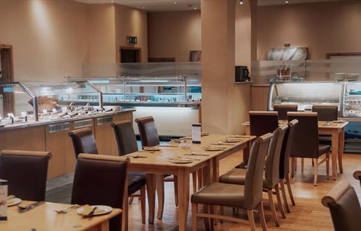 Spacious restaurant with carvery filled with numerous tables and chairs.