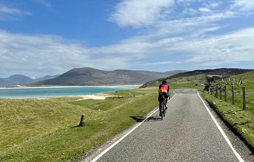 Cyclist passing beach in Harris