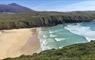 Mangersta Beach, Isle of Lewis. Looking down from sea cliffs onto turquoise waves breaking onto a white beach bounded by cliffs and a conical hill.