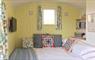 Interior of a Shepherd's Hut. A double bed made up with white bed linen and scatter cushions in floral designs.