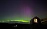 A green and pink aurora arcing across the night sky above a curved cabin at Mangersta Croft Holidays, Isle of Lewis.