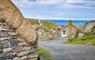 Gearrannan Village on the Isle of Lewis. Close up detail of blackhouse with stone walls and thatched roof. Sea views in the background.