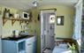 Interior of a Shepherd's Hut with a small kitchen, ensuite shower and dining table. The interior is painted yellow and blue.