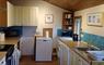 Kitchen viewed from entrance, Showing Cooker and cupboard units to the Left, Boiler at the end, and Washing machine, Dishwasher and Sink unit to the r