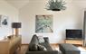 Mangersta Steading interior view of a stylish living room, with an ash sideboard, large leather sofa, TV with sound bar and original artworks.